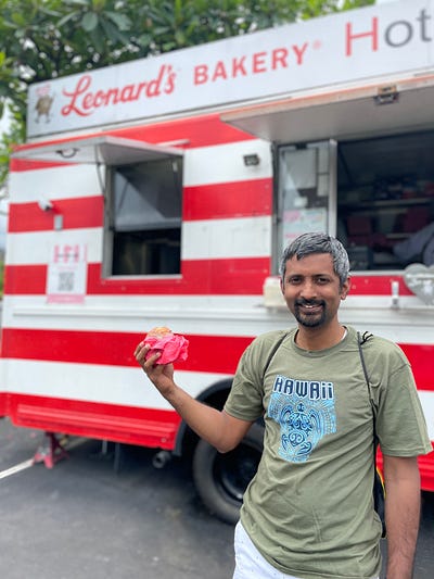 Showing off a malasada in front of a malasada truck