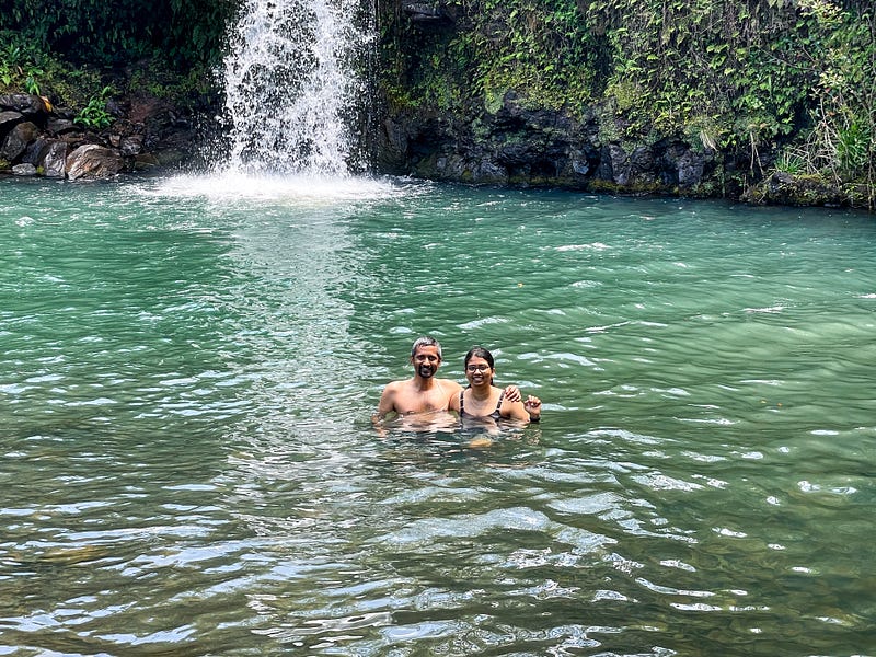 This image shows people inside a pool of water at the bottom of a water fall.